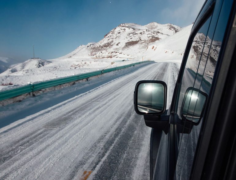 Driving on a snowy mountain road under a clear sky